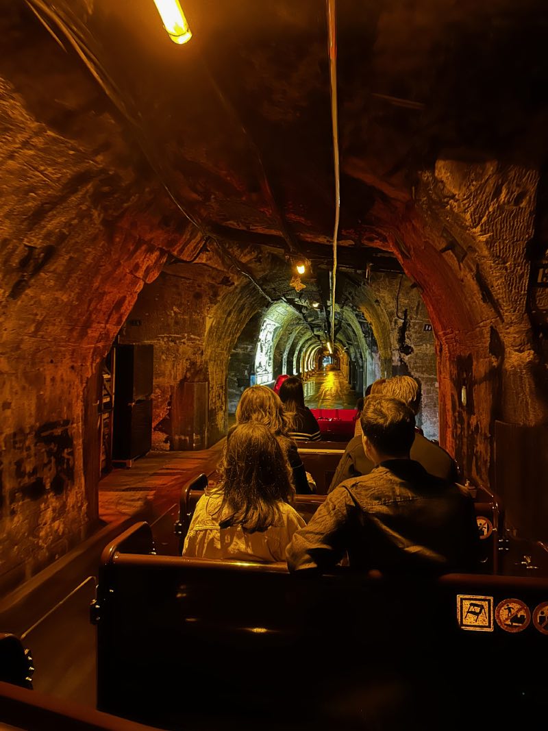 a stone tunnel with people riding in carts through it